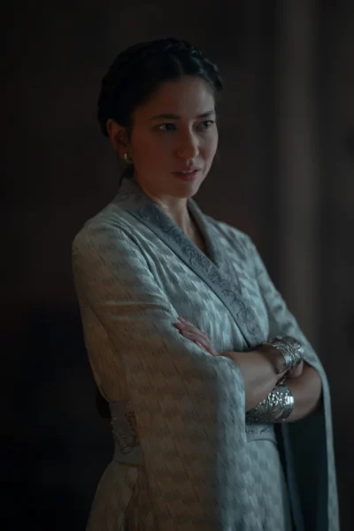 Mysaria con los brazos cruzados vistiendo una túnica con brazaletes plateados - House of the Dragon 3x05 - Temporada 3 Capítulo 5